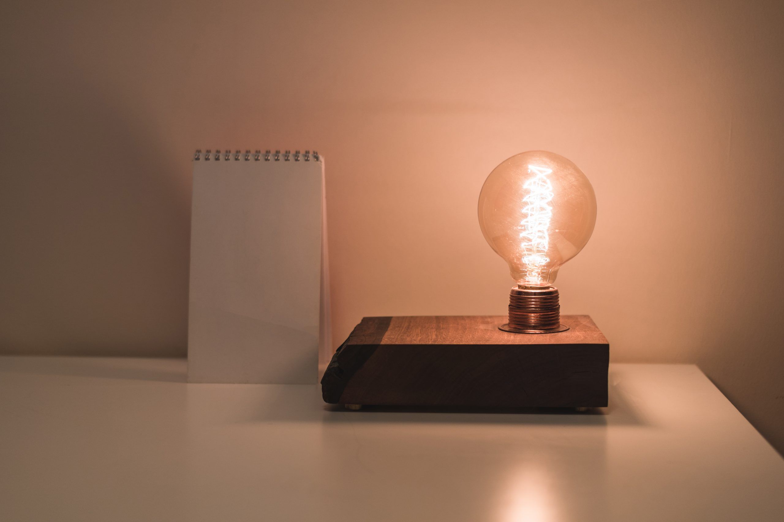 Clear bulb beside white notepad on white surface